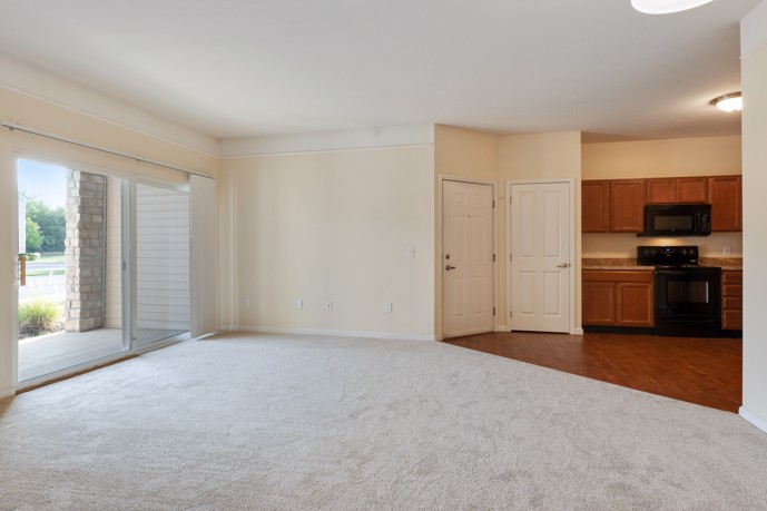 Spacious living room with a large sliding door opening to a private patio and convenient access to the kitchen.