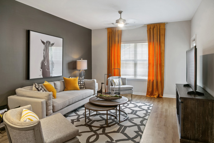 Comfortable living room adorned with track lighting, a ceiling fan, a window, access to an outdoor patio, and hardwood-style flooring.