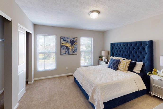 Bedroom with blue headboard and white bed, creating a serene and elegant atmosphere at Riverford Crossing. 