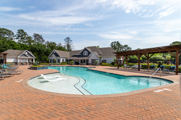 Outdoor resort-style swimming pool with verandas behind it on one side and apartment buildings behind it on the other