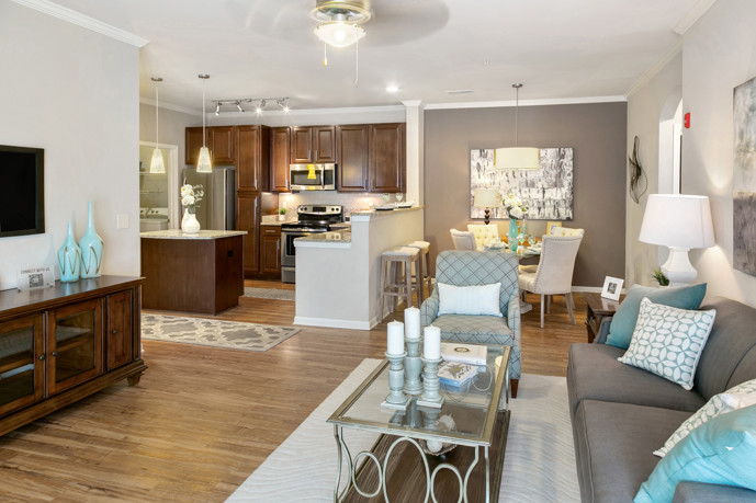 Cozy living room adjacent to a dining area, adorned with hardwood-style flooring and accessible from the hallway.