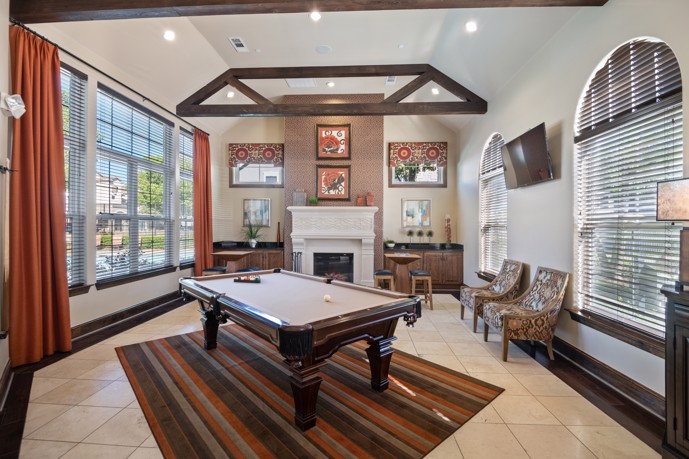 Clubhouse featuring a billiards table, ample seating, a cozy fireplace, and expansive windows.