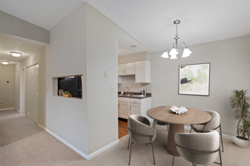 A cozy carpeted dining area with a ceiling light next to the kitchen in an apartment at the Villages at Spring Hill.