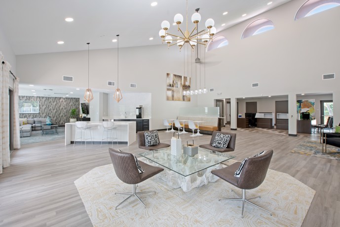 The spacious clubhouse at Vantage on Hillsborough, featuring lofty high ceilings, elegant wood-style floors, and a convenient kitchen bar, providing residents with a stylish and welcoming communal space for socializing and relaxation.