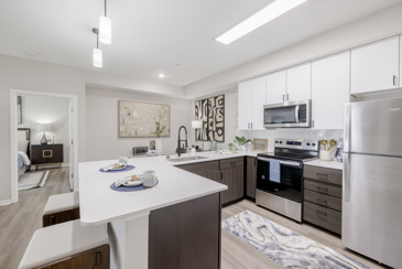 A modern kitchen at The Chelsea apartments with a white countertop and wood-style cabinets.