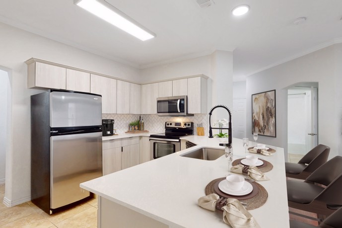 U-shaped kitchen boasting a breakfast bar, stainless steel appliances, and stylish tile flooring.
