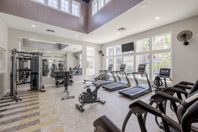 The newly renovated fitness center at The Chelsea apartments in Columbus, Ohio, boasting large windows that flood the space with natural light and a diverse selection of gym equipment for residents' workouts.