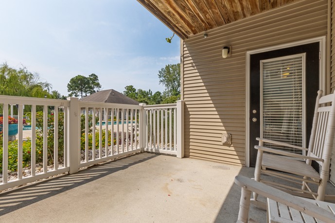 Outdoor apartment patio overlooking the swimming pool at Cherry Grove Commons apartments in Sunset Beach, SC