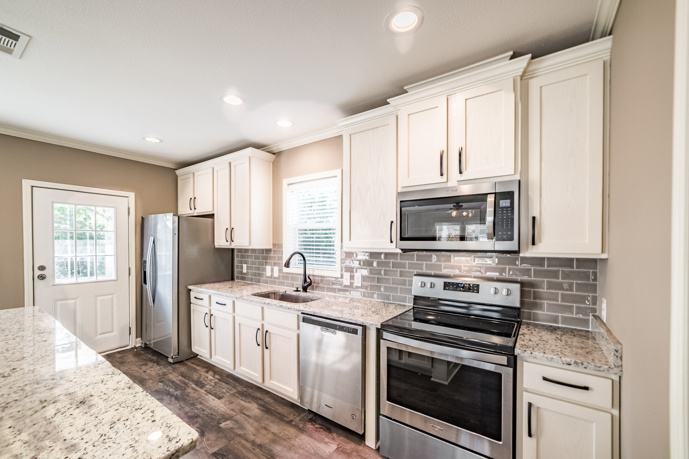 A stylish apartment at Virtuoso apartments in Huntsville, AL, featuring wood-style flooring and an open floor plan that includes a kitchen with a granite counter bar.
