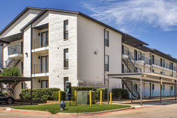 The inviting exterior of the apartments at Vue at Knoll Trail with a pathway and foliage in front of it.