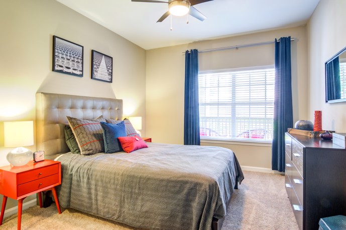A comfortable bedroom in Reflections on Sweetwater, featuring modern furnishings, a cozy bed, and stylish decor.