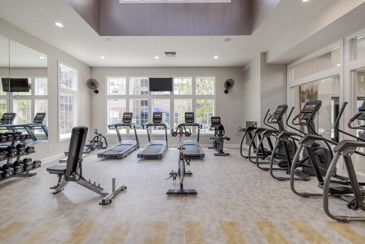 The Chelsea fitness center with gym equipment, large windows, and TVs.