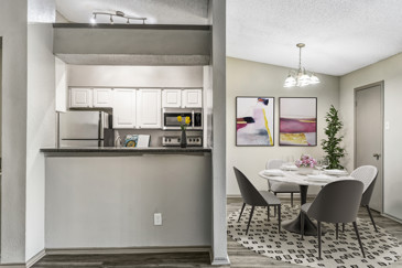 An open-concept apartment with a kitchen next to the dining room at Vue at Knoll Trail in Dallas, TX.