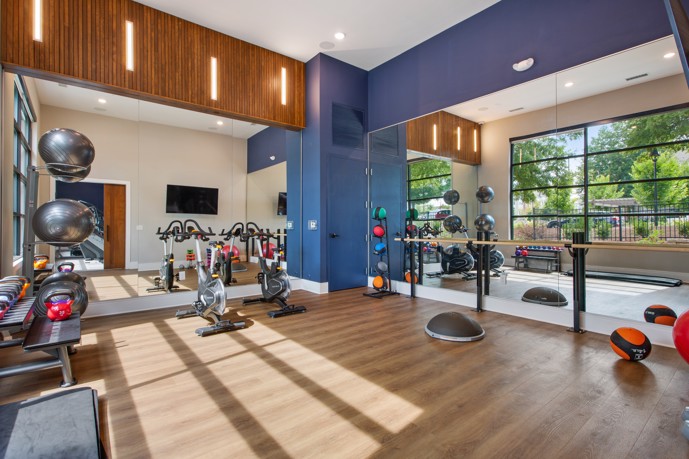 Vesta City Park offers a state-of-the-art fitness center, featuring high-quality gym equipment, large mirrors, and a vibrant blue wall that adds a pop of color to your workout routine.