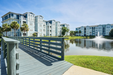 Scenic walking trail and pond at The Enclave at Tranquility Lake surrounded by lush greenery and featuring a tranquil water surface reflecting the natural surroundings.