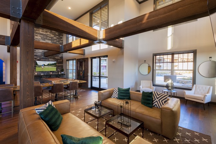 Clubhouse offering various lounges, seating areas, a billiards table, television, and adorned with large wooden beams.