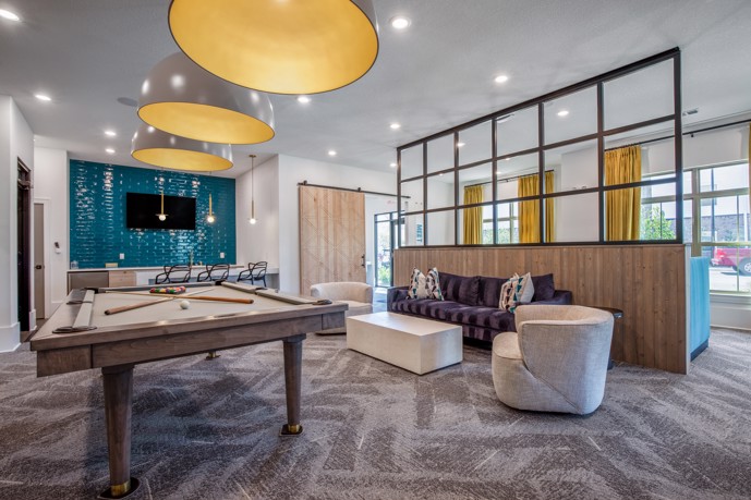Community clubhouse with a seating area and pool table at Cyan Mallard Creek apartments in Charlotte, NC