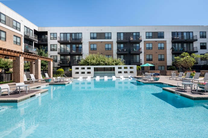 A refreshing community pool area, featuring a spacious sundeck and inviting lounge chairs for residents to bask in the sun and unwind.