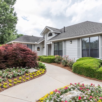 A pathway with flowers leading to the large clubhouse at Pointe at Canyon Ridge in Atlanta, GA.