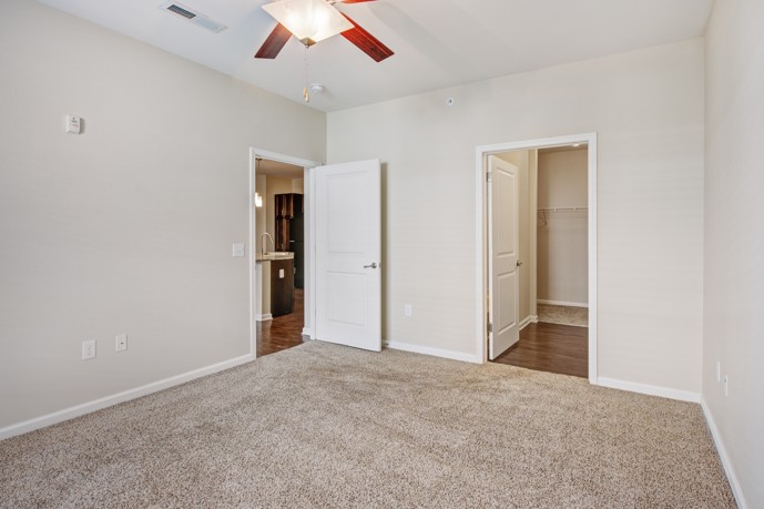An empty bedroom with brown carpet and a ceiling fan.