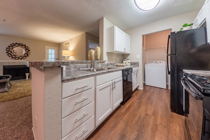 A modern kitchen with white cabinets and sleek black appliances at the 1800 at Barrett Lake apartments.