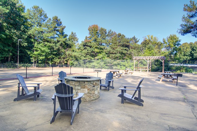 A fireside lounge with lawn chairs surrounding the brick firepit.