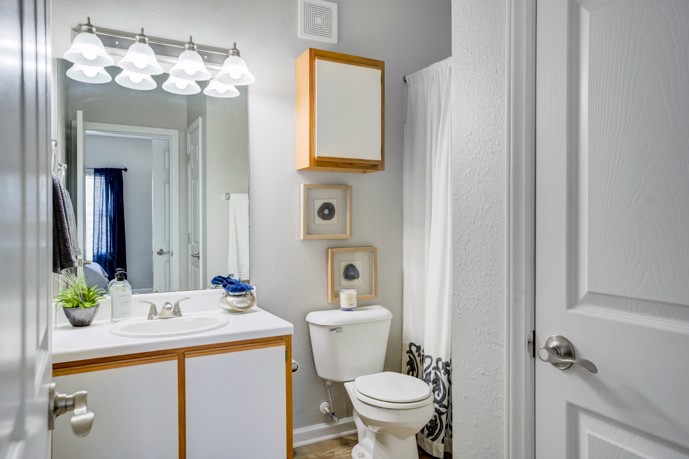 Bathroom complete with a sink, expansive mirror, toilet, and shower facilities, offering convenience and comfort.