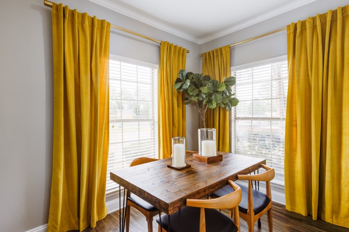 A sunlit dining area boasting ample natural light streaming in through large windows, furnished with a table surrounded by chairs, within a Walnut Hill apartment.
