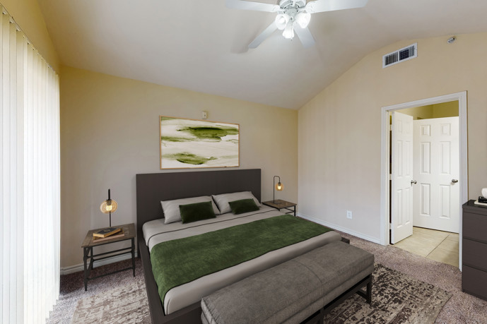 A cozy bedroom featuring a ceiling fan, plush carpeting underfoot, and sliding doors leading to a private balcony.