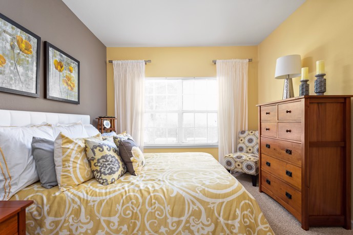 Calm and bright furnished yellow and grey apartment bedroom with a large window