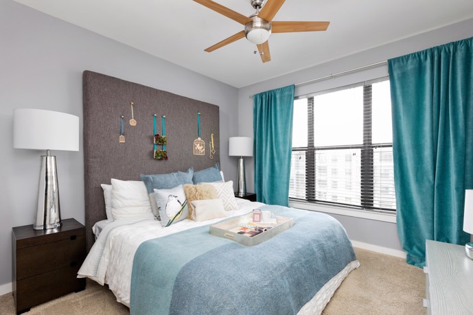 A bedroom, boasting a large window, plush carpet flooring, and a convenient ceiling fan.