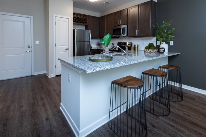 Well-appointed L-shaped kitchen boasting granite countertops, stainless steel appliances, hardwood-style flooring, and a breakfast bar.