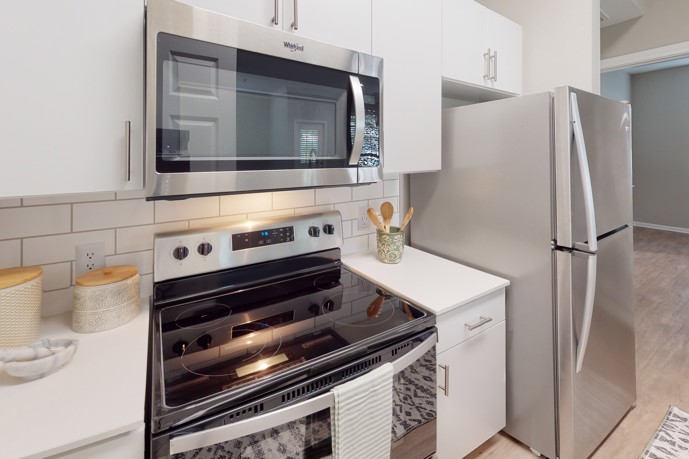 Well-appointed kitchen equipped with stainless steel appliances, white cabinets, subway-style tile backsplash, and hardwood-style flooring.
