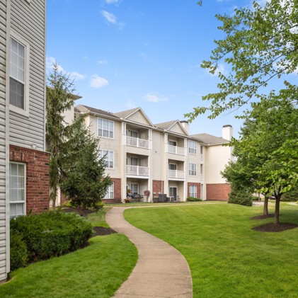 Exterior view of a cement path leading through a lawn up to Avalon Oaks apartment buildings in Columbus, OH