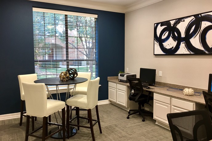 The business center at The Delano at North Richland Hills, in Richland Hills, TX, equipped with a table and computer station, providing residents with a convenient workspace.