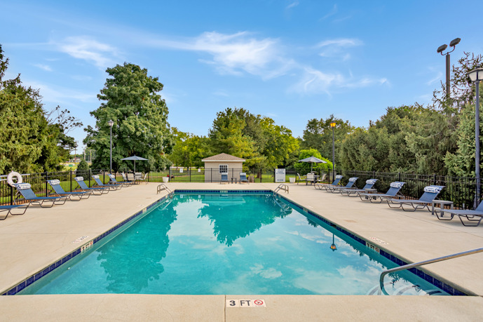 A spacious pool area positioned in front of the clubhouse at Spring Hill in Nashville, Tennessee, providing residents with a serene outdoor oasis for relaxation and recreation.