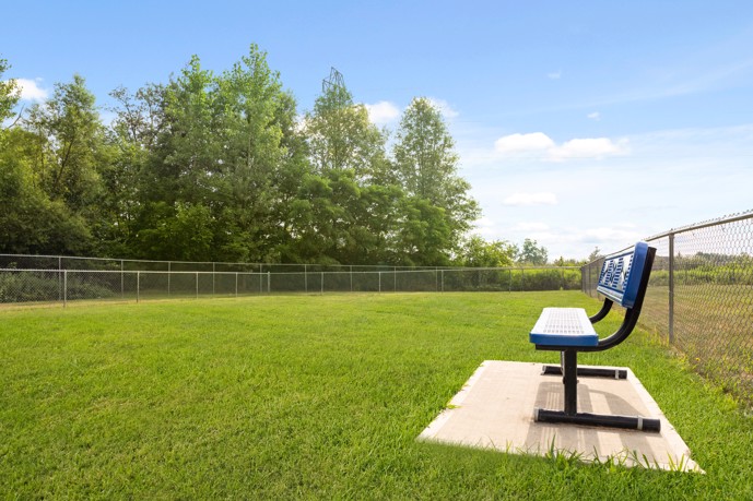 Fenced-in lawn and dog park with a blue bench at Avalon Oaks apartments in Columbus, OH