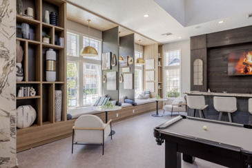The clubhouse at The Chelsea with a pool table, tables with seating, and shelving. 