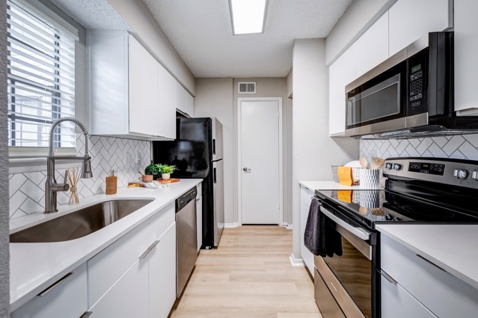 Kitchen equipped with cabinets, stainless steel appliances, a window for natural light, and hardwood-style floors.